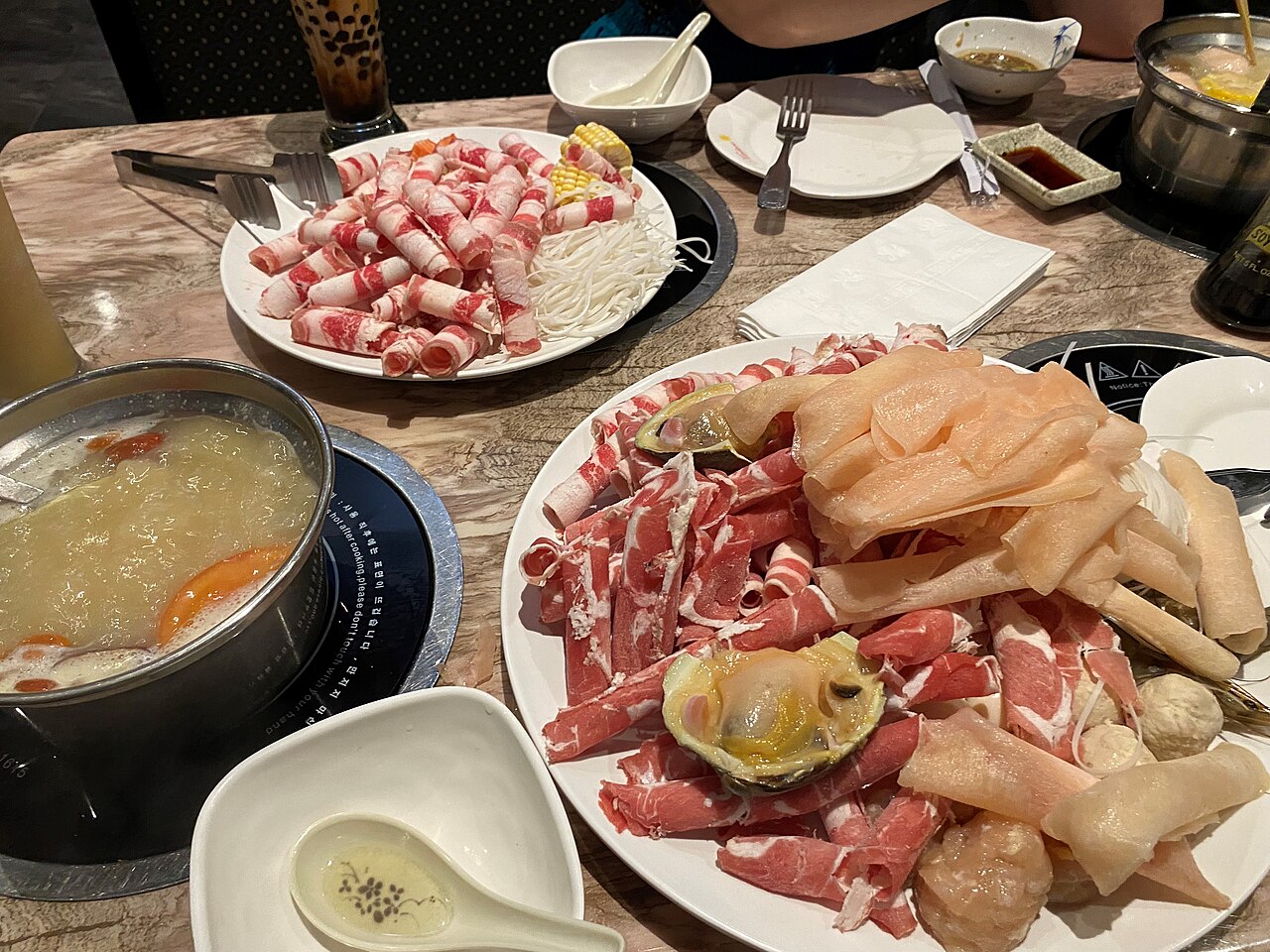 A hot pot spread with thin-sliced meat in broth
