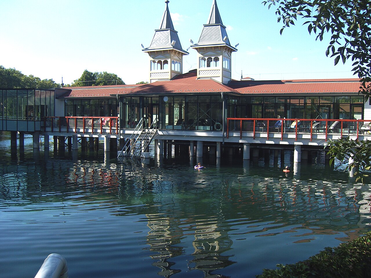 The central bath building of Lake Hévíz standing on piles over the water, with bathers floating nearby