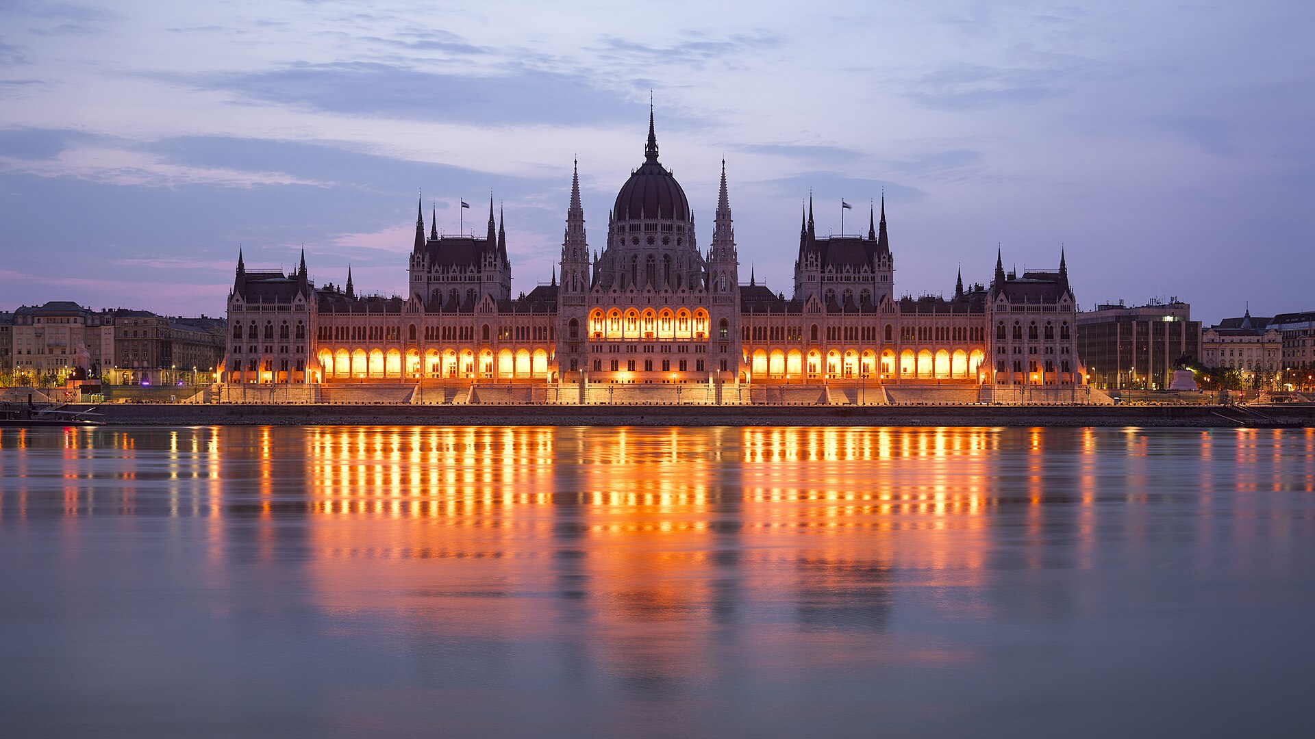 The Hungarian Parliament Building lit up at dawn, photographed across the Danube from the Buda embankment beside Batthyány tér