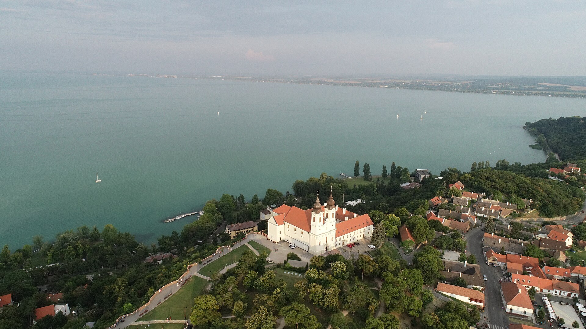 Aerial view of Tihany Abbey on its hilltop above the village, with Lake Balaton and sailing boats stretching out behind it