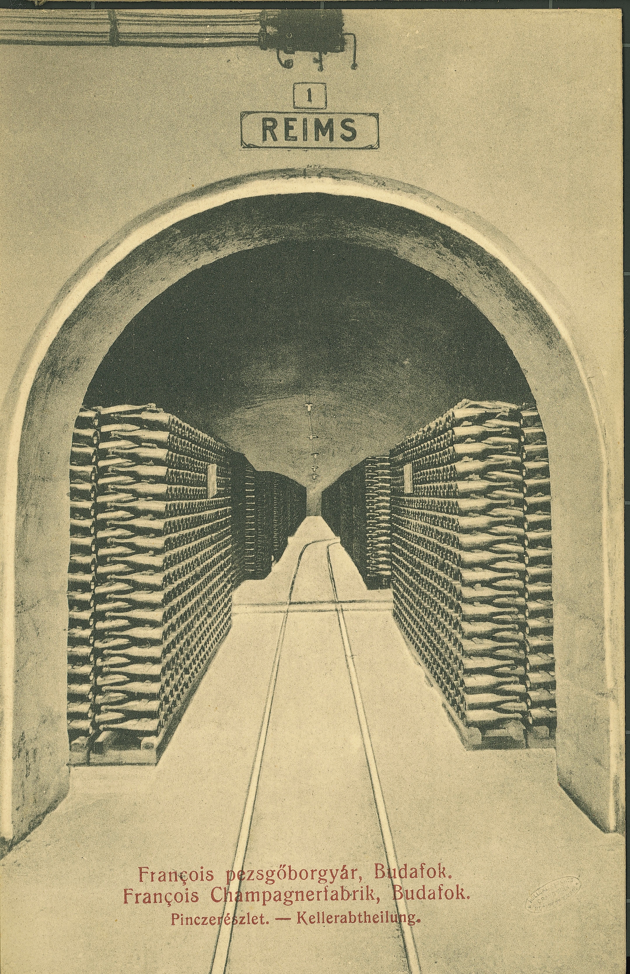 A printed postcard from around 1910 showing riddling racks and a rail track running down a limestone cellar tunnel in Budafok