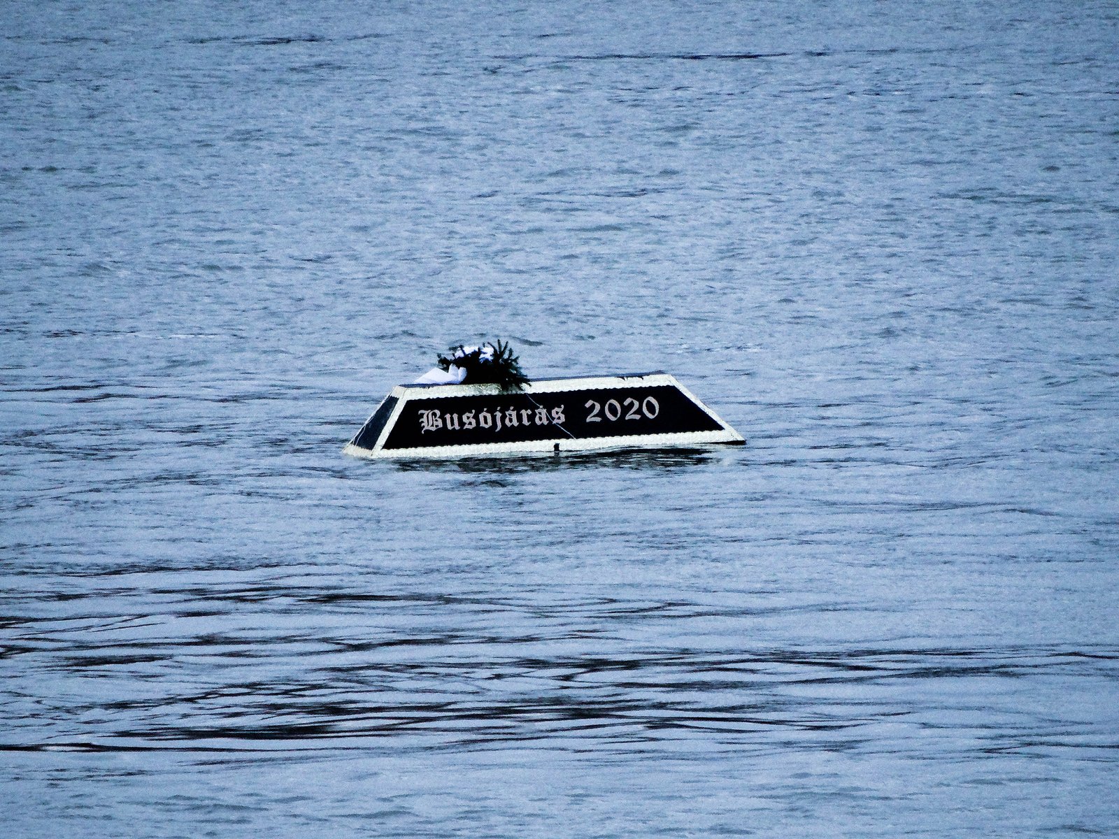 A black coffin lettered Busójárás 2020 floating alone on the Danube at Mohács