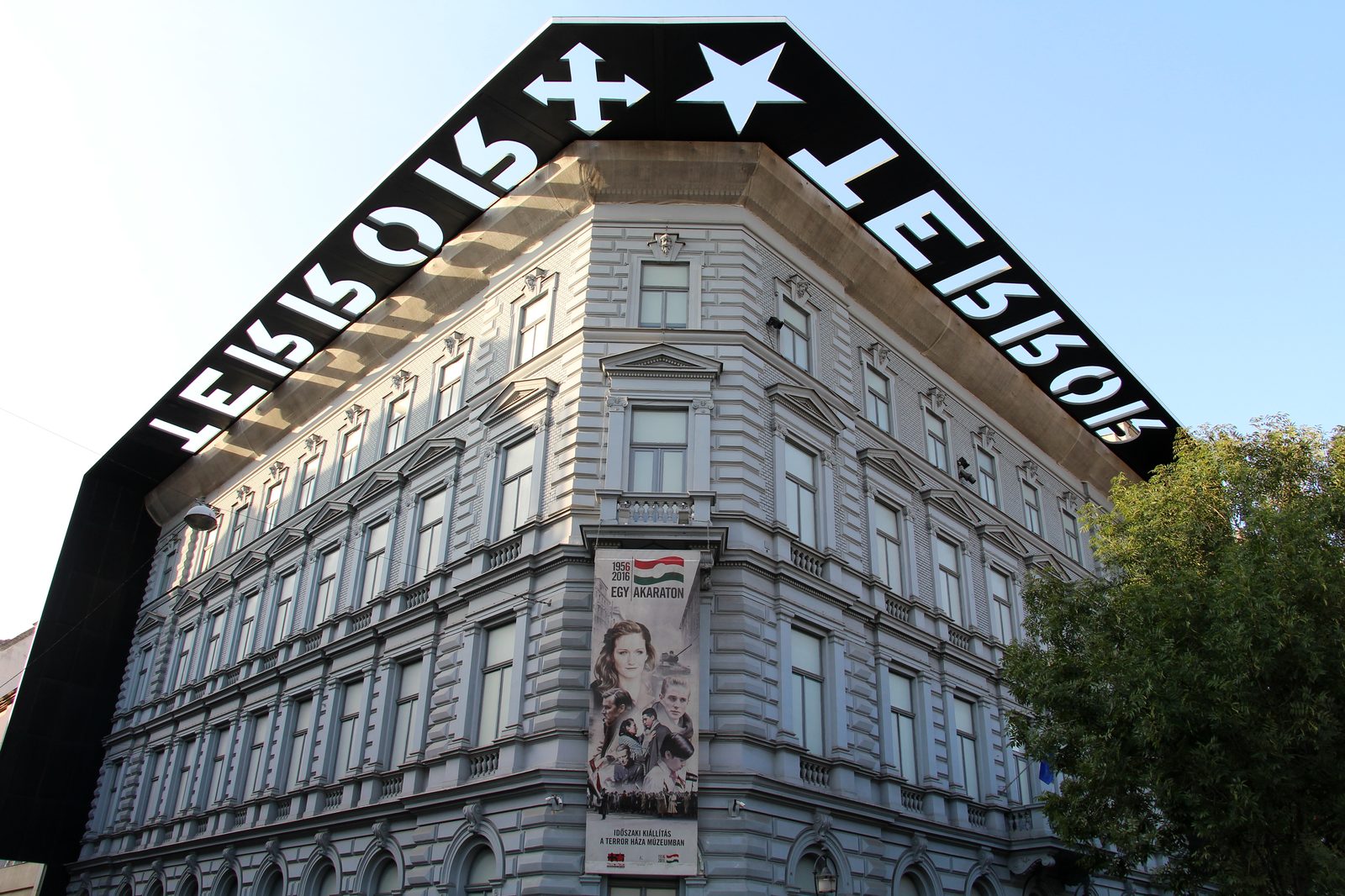 The corner facade of the House of Terror at Andrássy út 60, its black cornice cut with the word TERROR against the sky