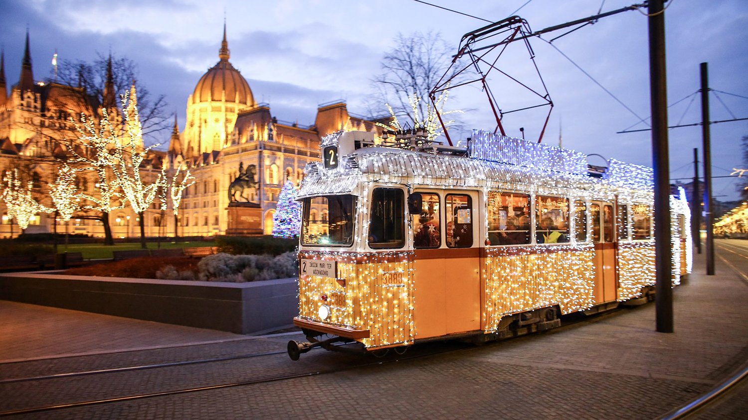 The fényvillamos Christmas light tram passing near the Parliament building on Kossuth tér, Budapest