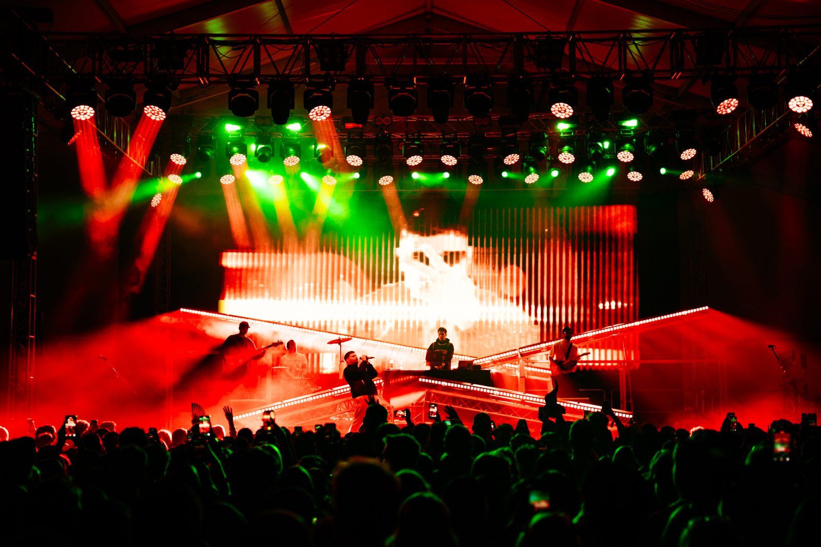 A night concert on the festival’s main stage, red and green lights over the band and a crowd holding up phones