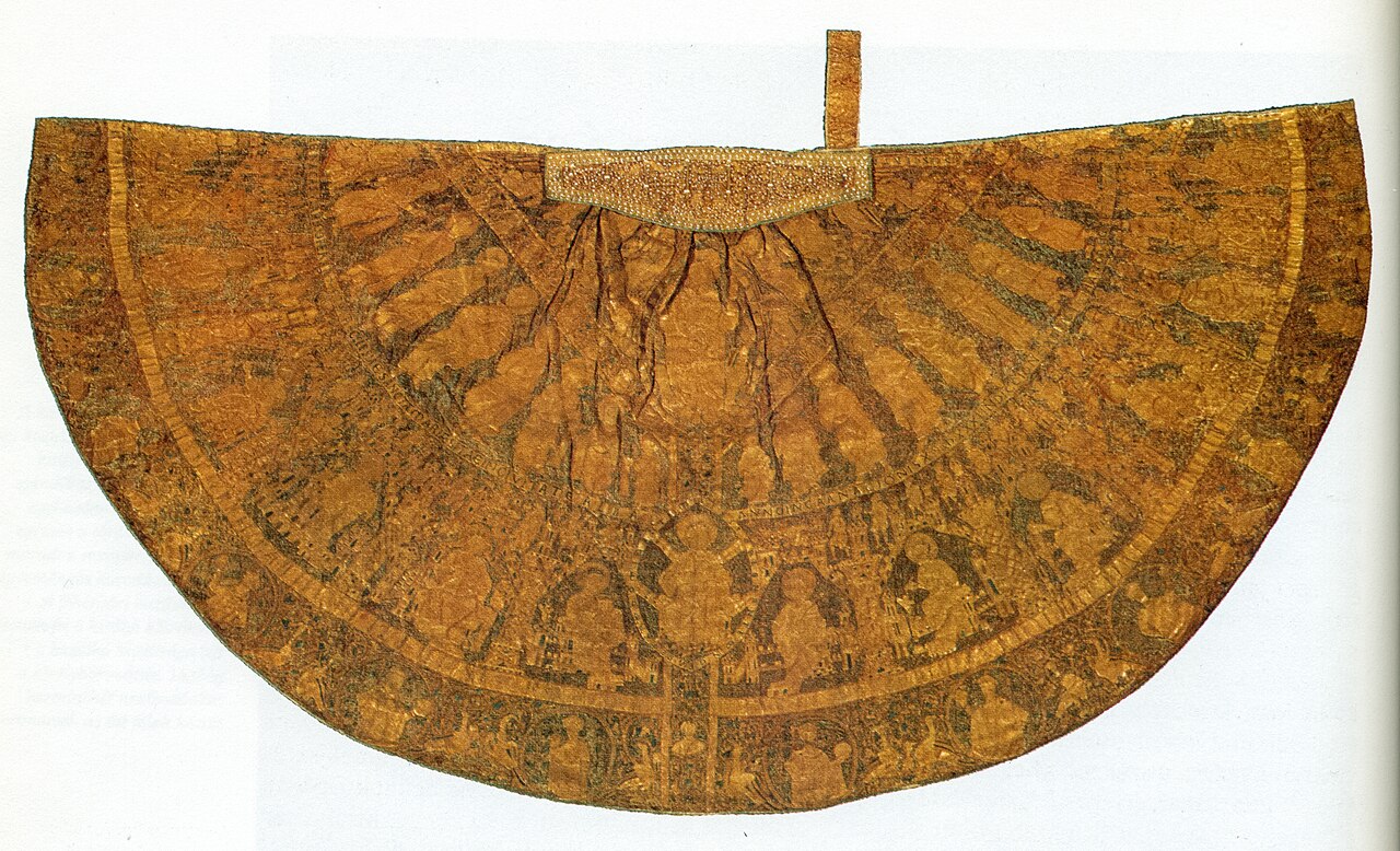 El manto de coronación húngaro: una prenda semicircular de seda dorada, bordada casi de borde a borde, con hileras de figuras bajo arcos y una banda de cuello con pedrería.