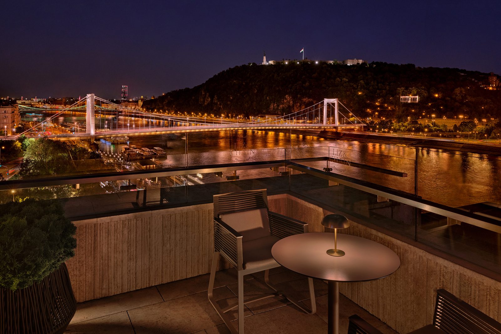 The Liz side of the terrace at night, the floodlit Elisabeth Bridge and Gellért Hill with the Citadella behind the tables