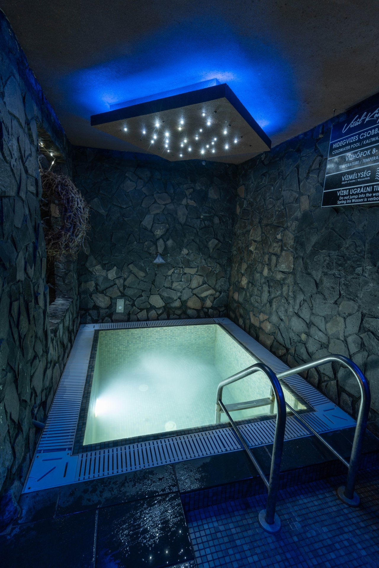 A cold-plunge pool in the Vitál Centre at Aqualand Ráckeve, lit blue in a stone-walled room