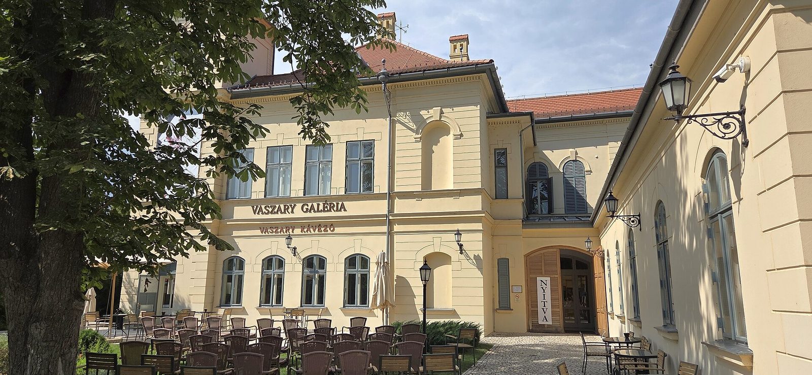 The yellow facade of the Vaszary Villa in Balatonfüred, with its gallery sign and café terrace