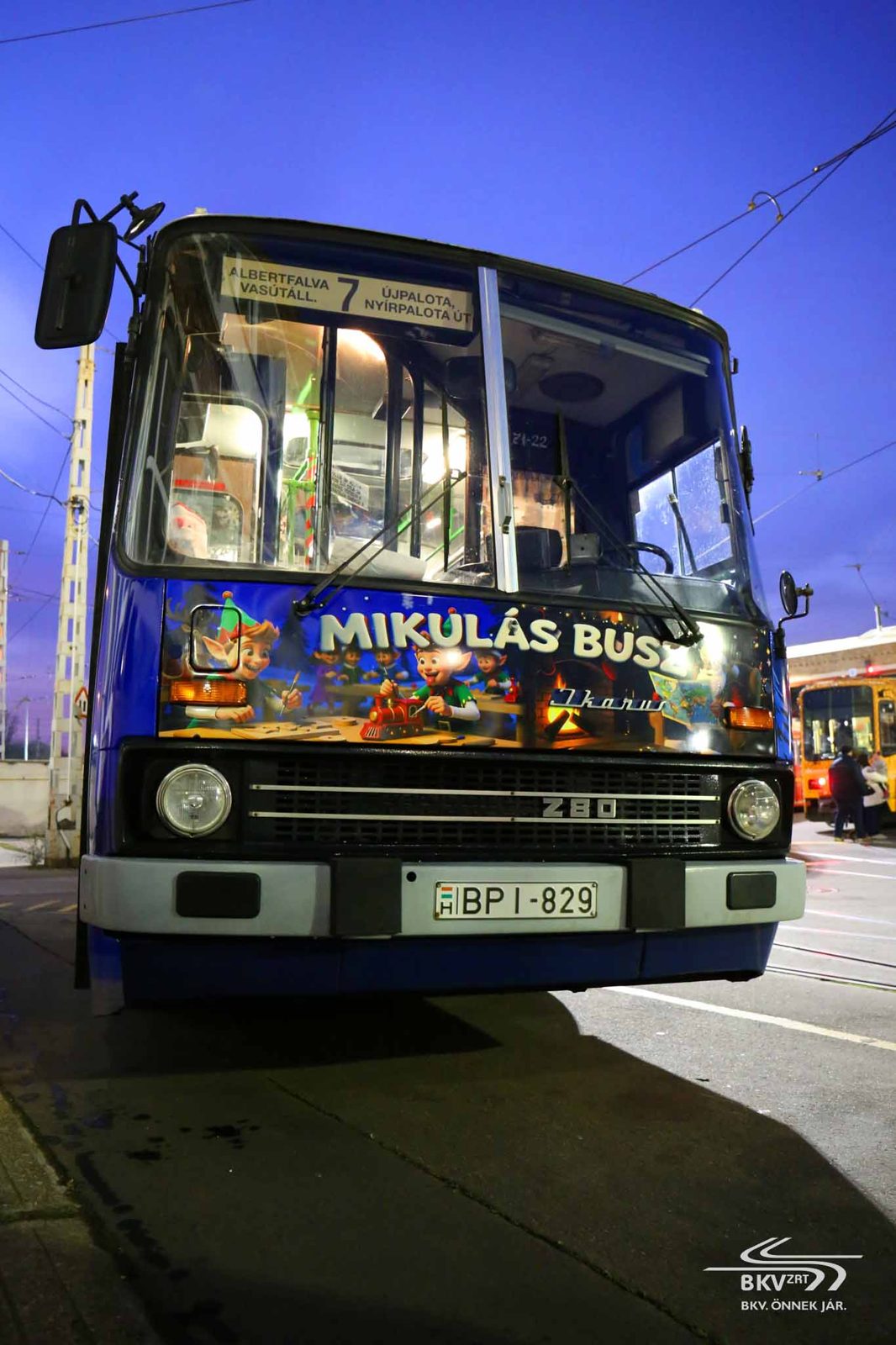 Modrý Ikarus 280 BKV jako Mikulásbusz za soumraku, s nápisem MIKULÁS BUSZ a kreslenou výzdobou na přídi, na lince 7