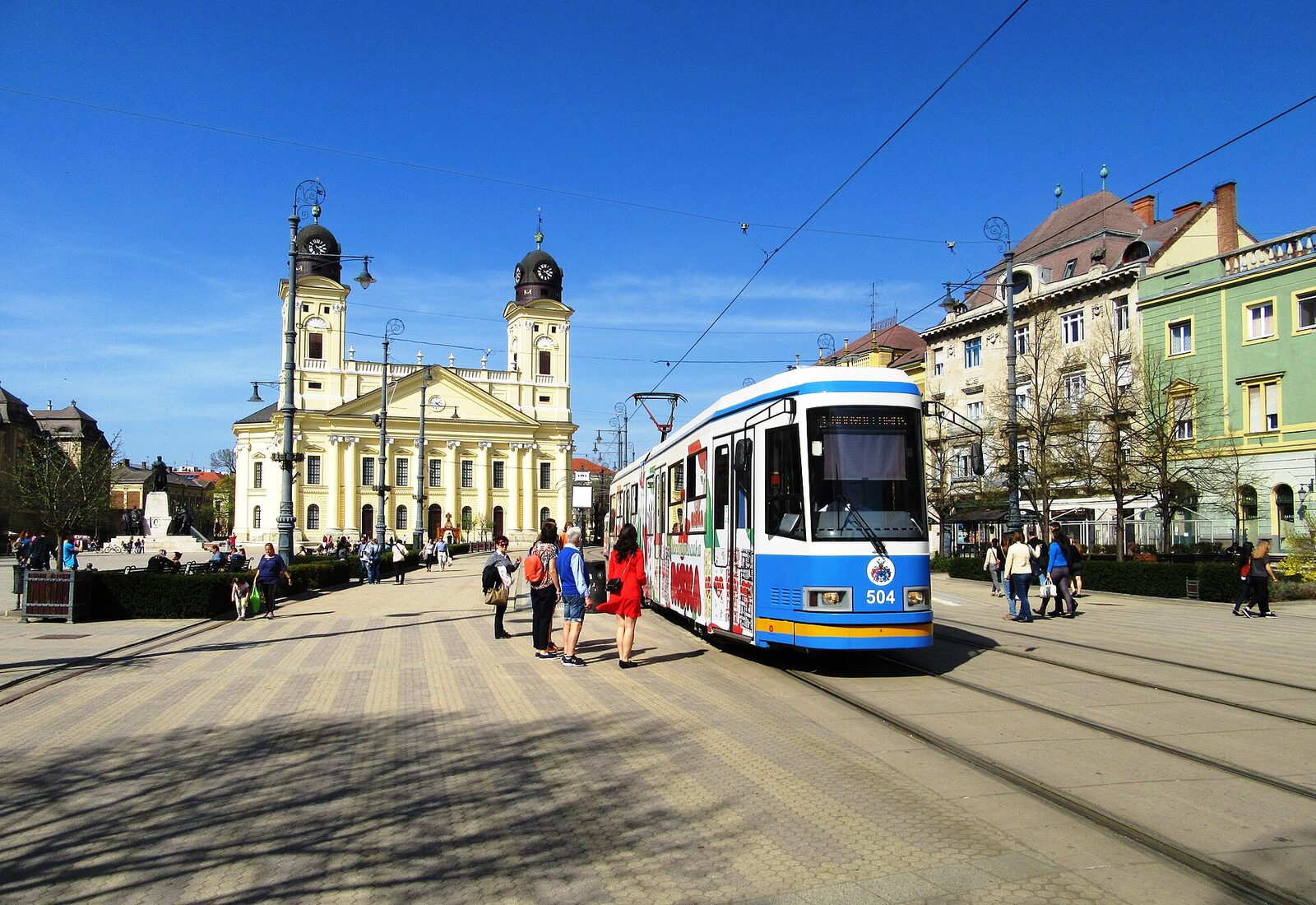 A tram on Kossuth tér in Debrecen, with the yellow twin towers of the Great Church behind it