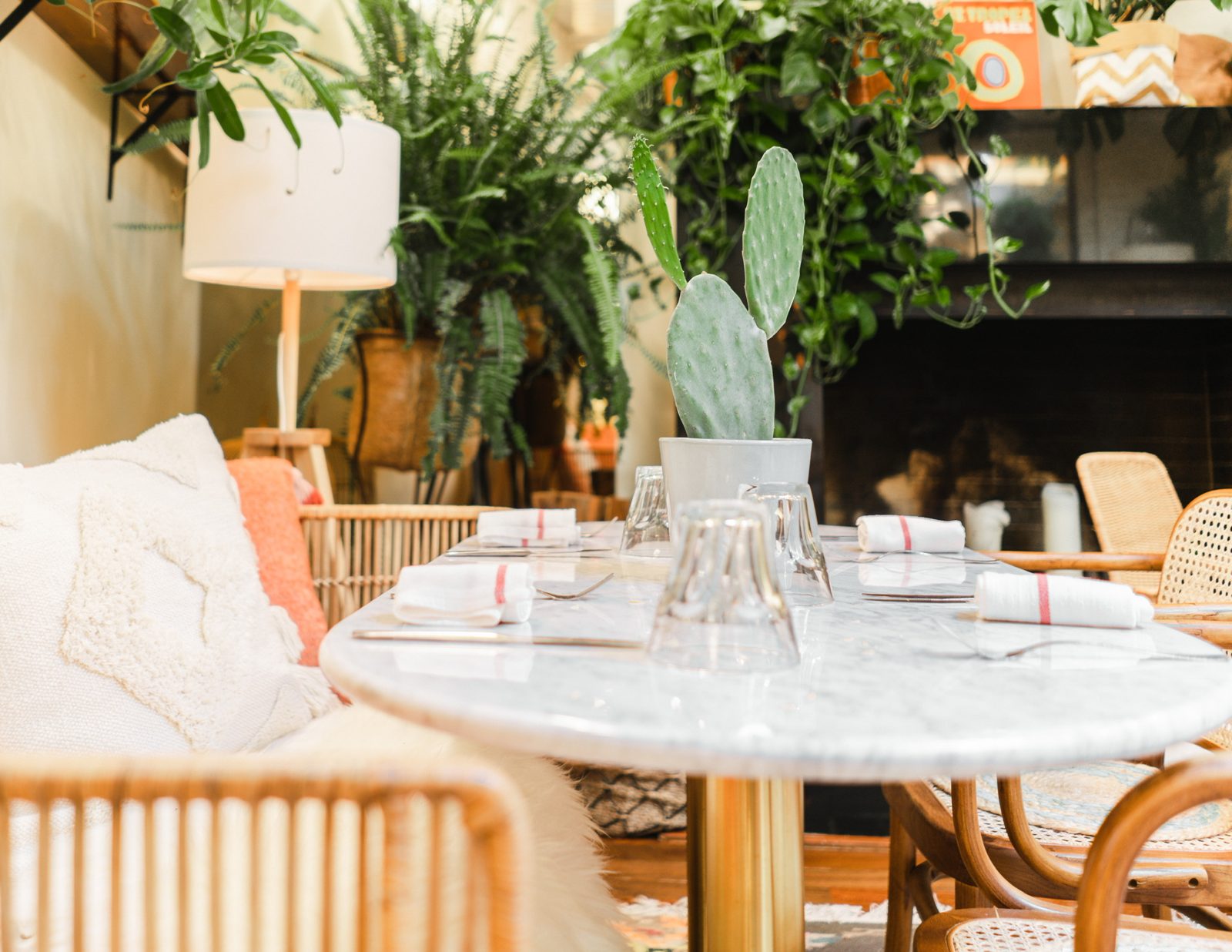 A laid marble table at Déryné with a potted cactus, rattan chairs and a cushioned bench