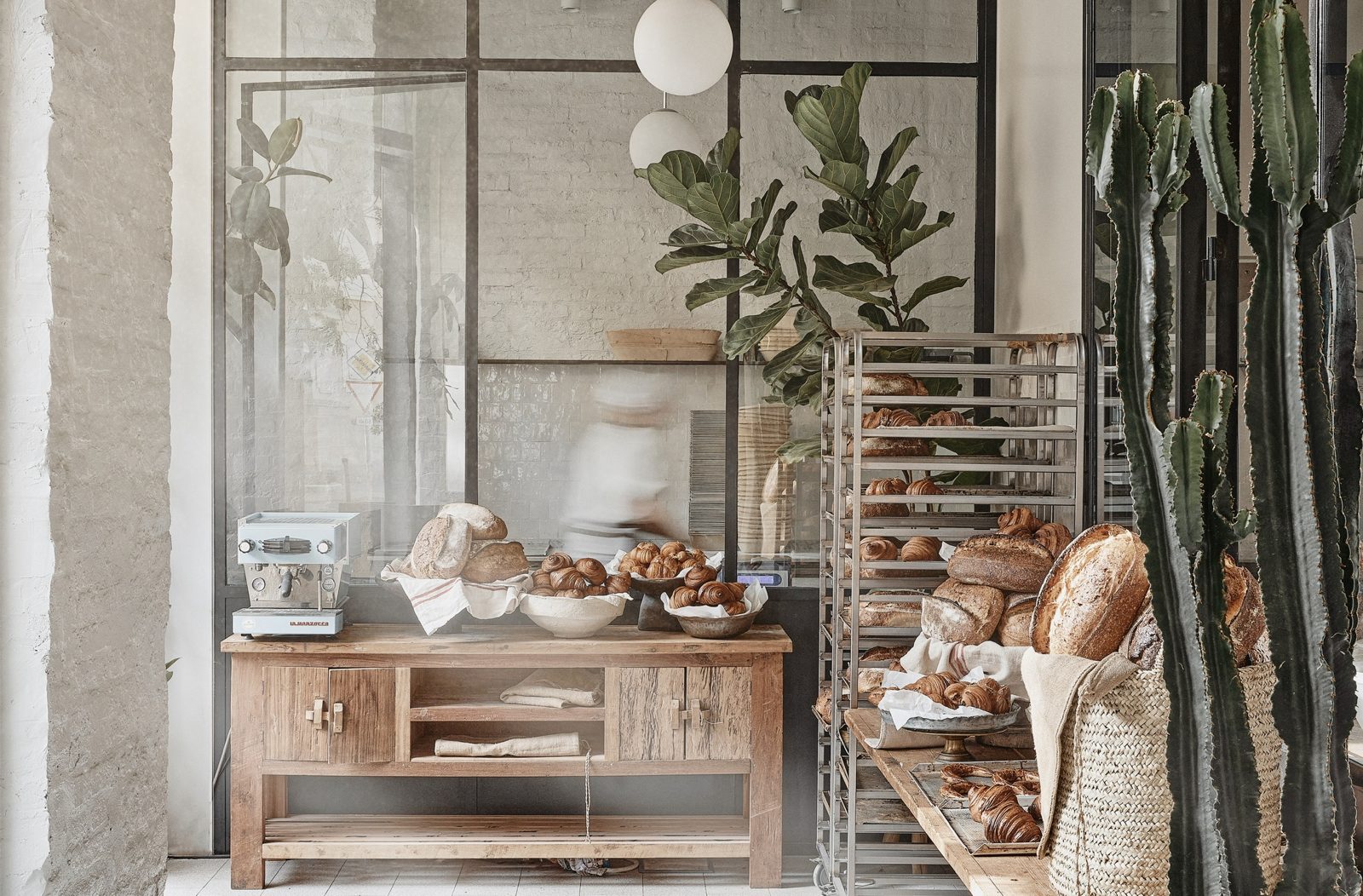 The Déryné Kenyér bakery counter with sourdough loaves and croissants, the glass-walled bakehouse behind