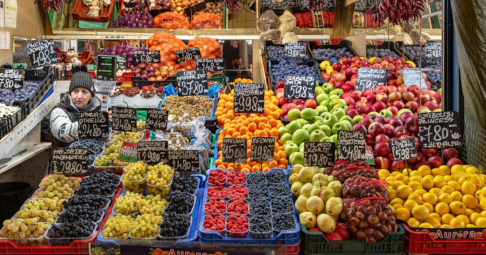 A fruit stall on the ground floor of the Great Market Hall, with grapes, berries, apples and handwritten price boards