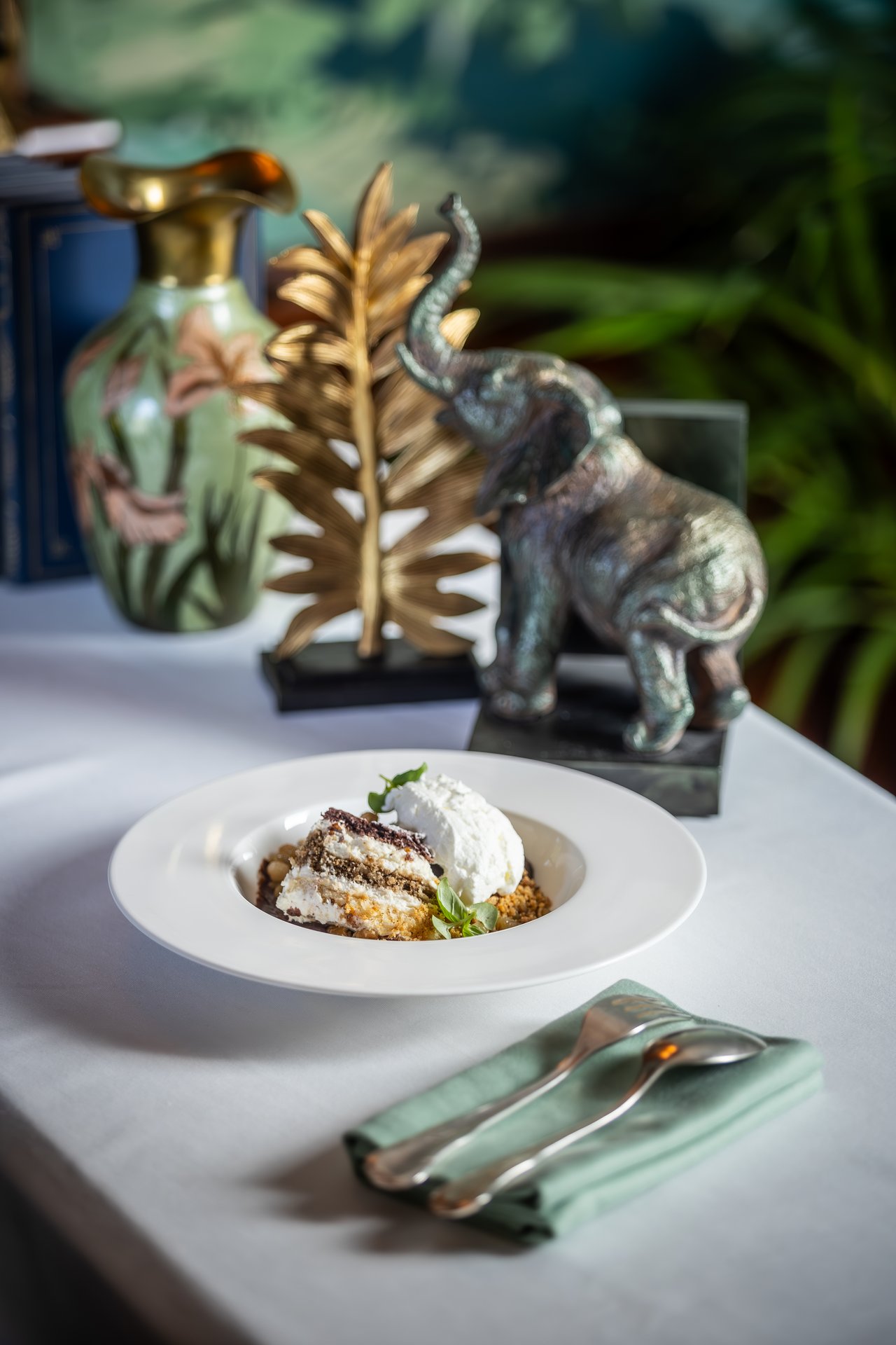 La somlói galuska del Gundel in un’ampia fondina bianca: strati di pan di Spagna e crema con una quenelle di panna montata, granella di noci, uvetta e salsa al cioccolato