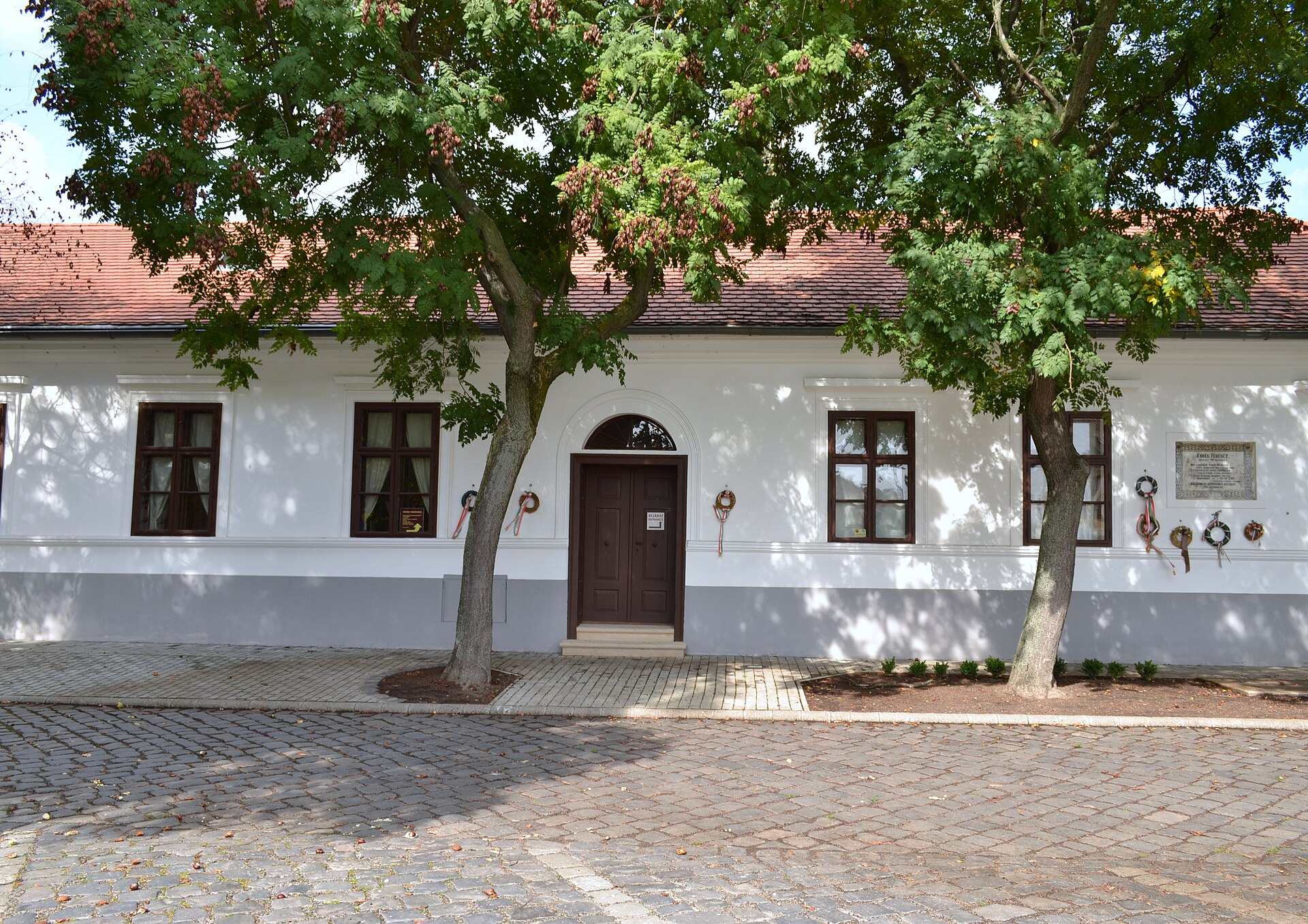 The white facade of Ferenc Erkel’s birth house in Gyula, with memorial wreaths