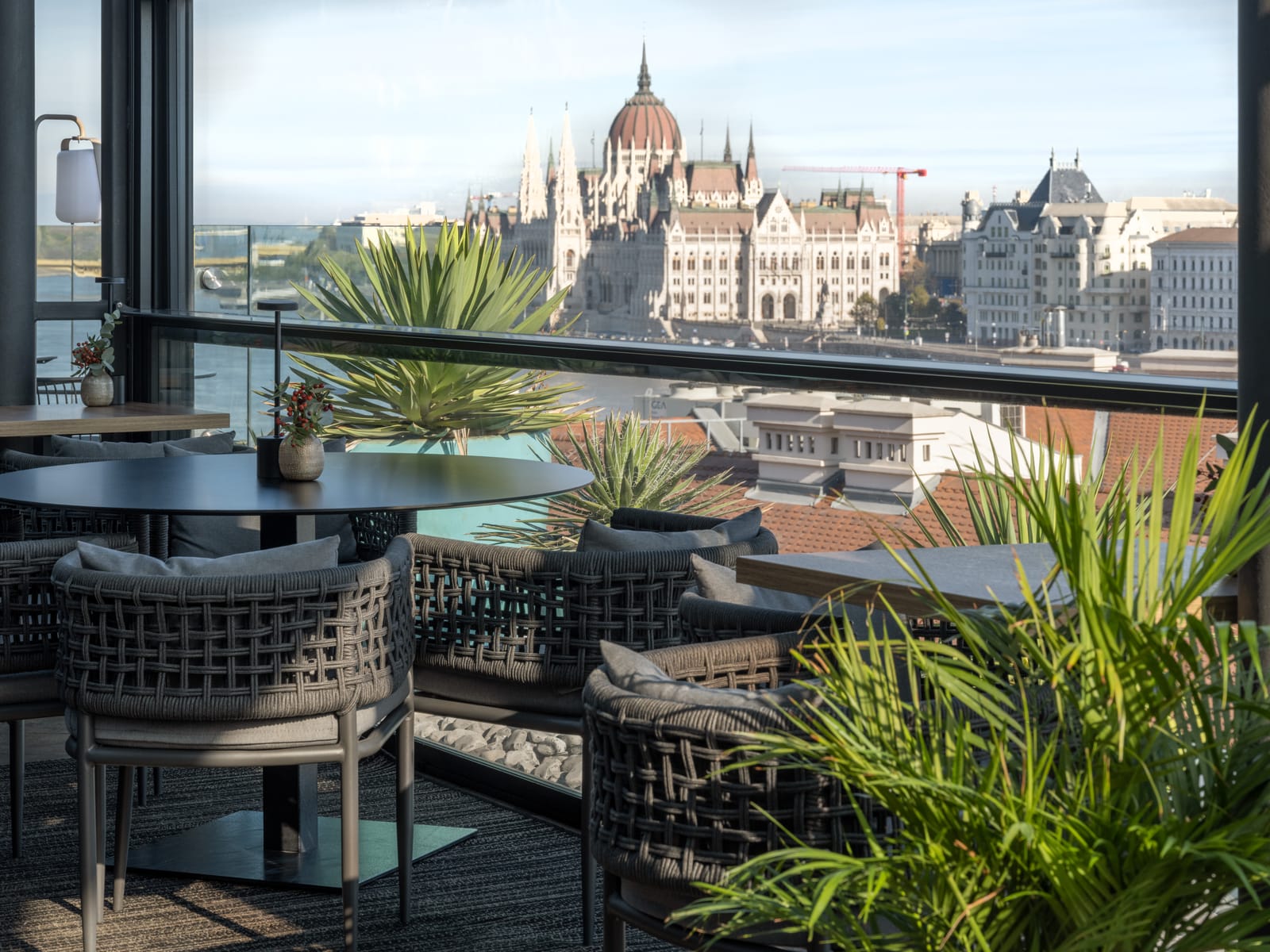 Woven armchairs at Leo Rooftop, with the Hungarian Parliament across the Danube