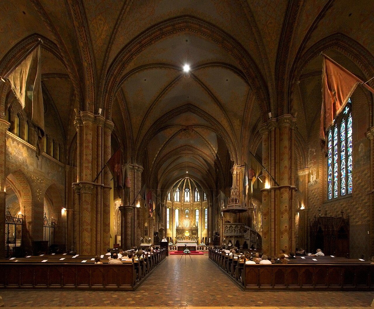 The nave of Matthias Church in Budapest, with painted columns and vaults leading to the high altar