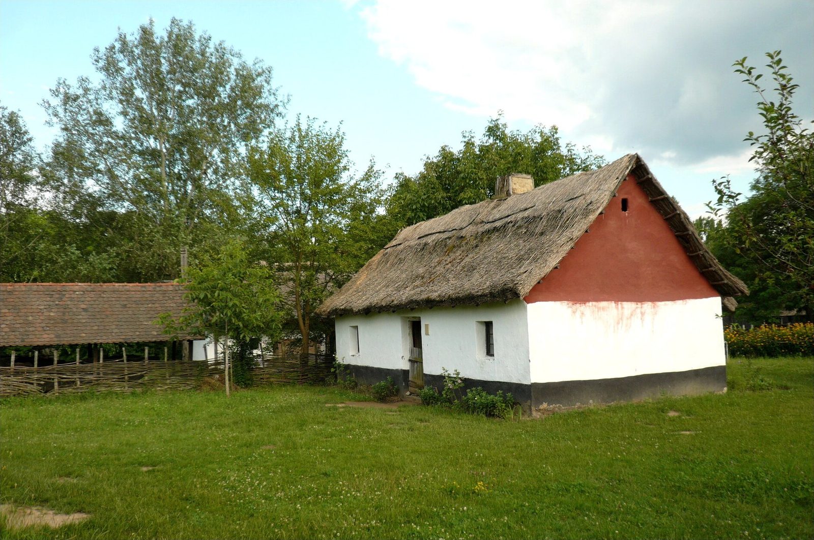 A whitewashed thatched farmhouse with a red gable at the Sóstó Museum Village in Nyíregyháza