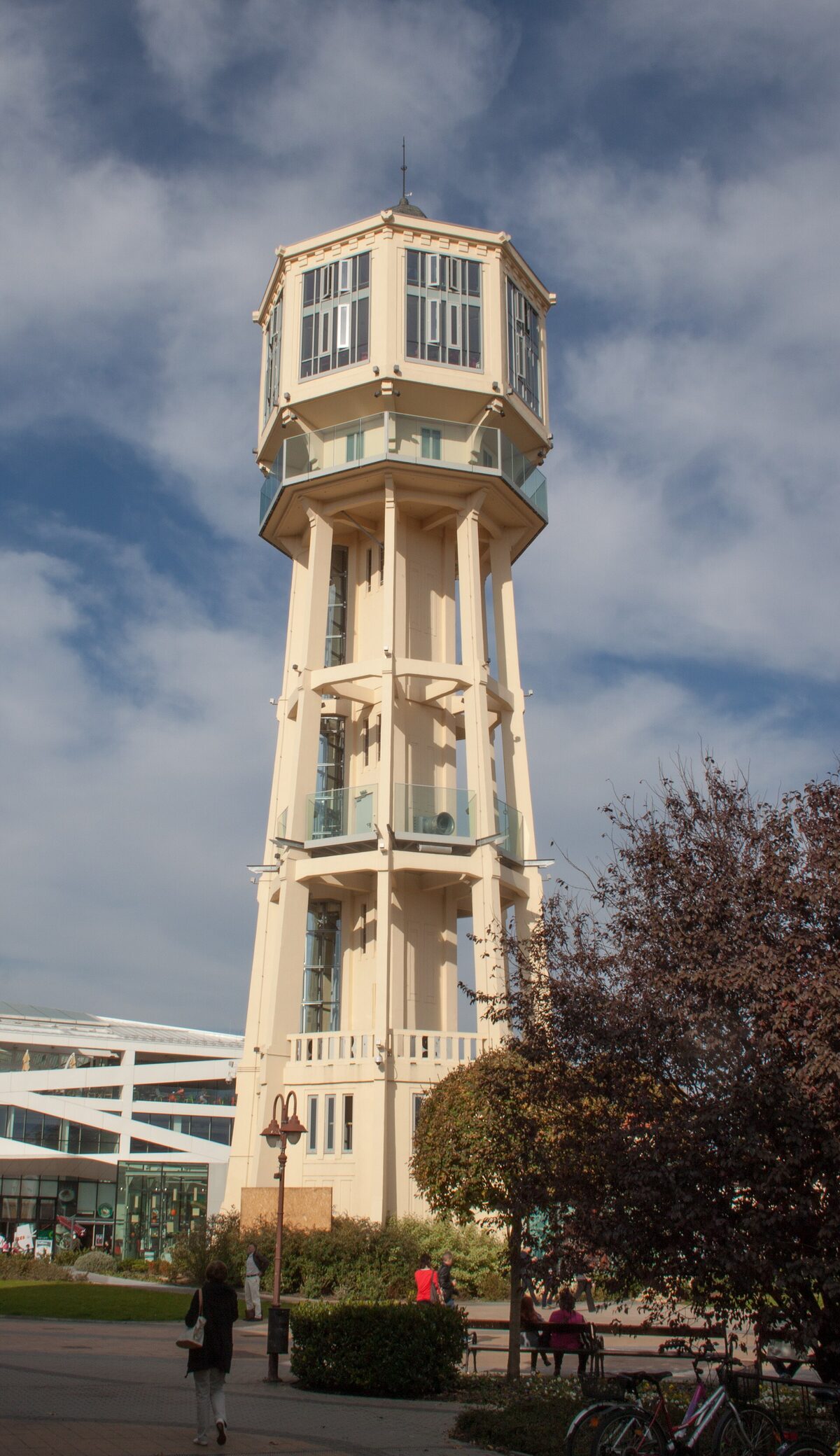 Siófok Water Tower, a tall cream-colored octagonal tower with a glazed lookout at the top, standing over a square with trees and bicycles