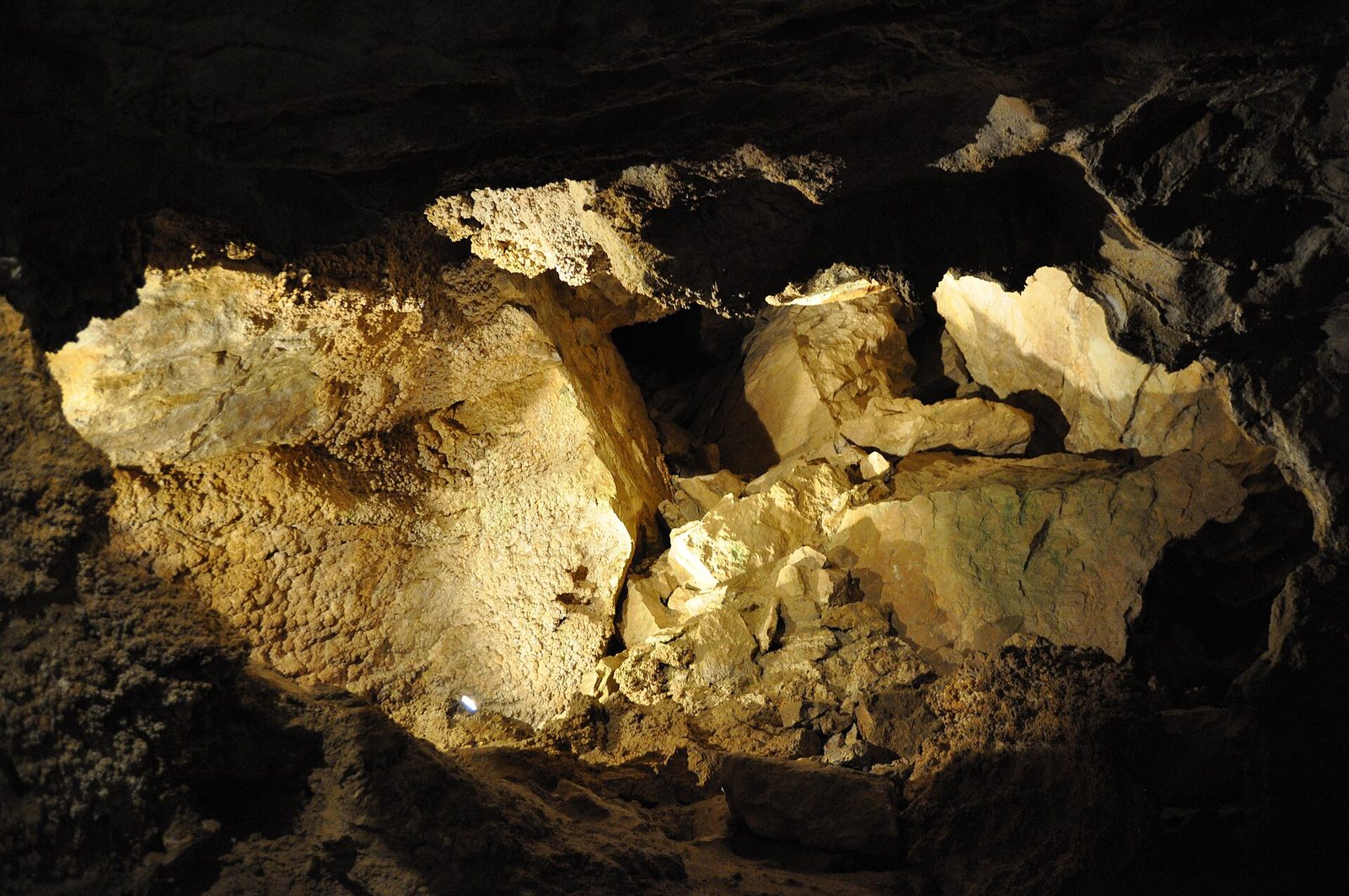 Lit limestone blocks and walls coated in knobbly mineral crusts inside a chamber of the Szemlő-hegyi Cave