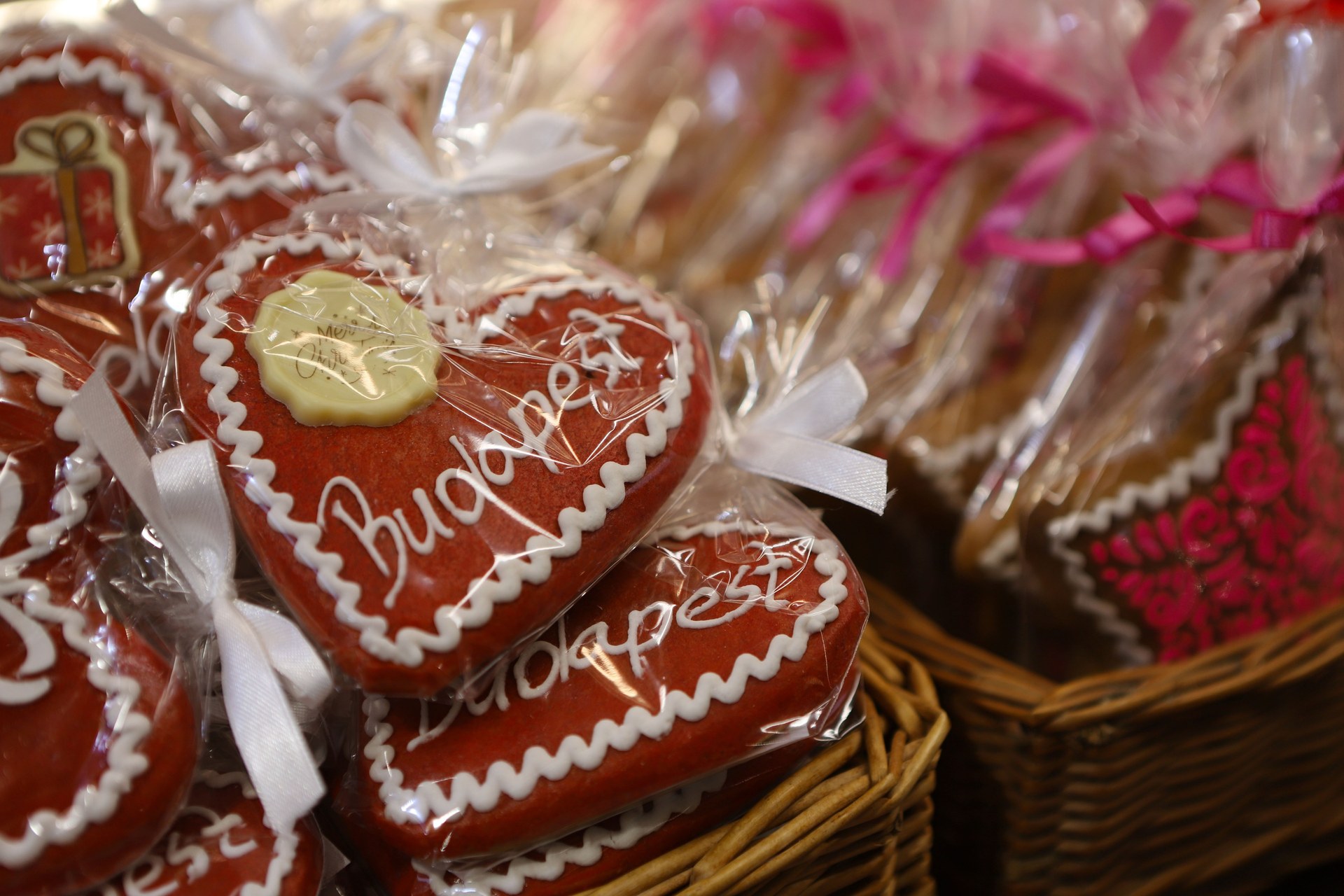 Gingerbread hearts iced with the word Budapest, wrapped in cellophane with ribbons in a wicker basket at the 2025 Christmas market on Vörösmarty tér